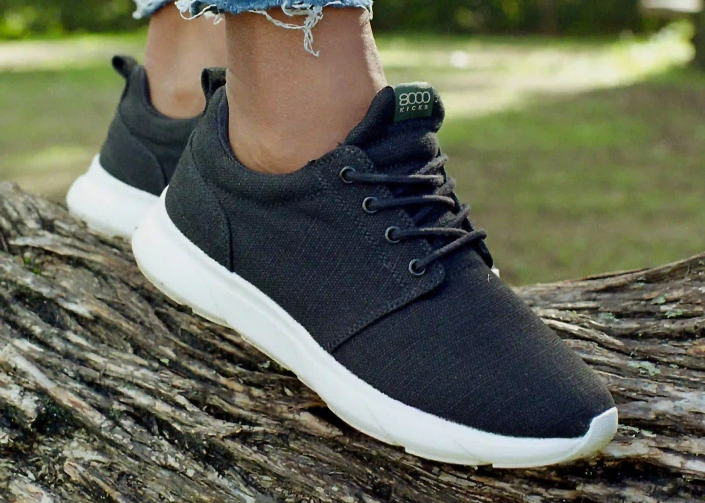 A woman stands on a tree trunk in her black and white Explorer V2 shoes for women.